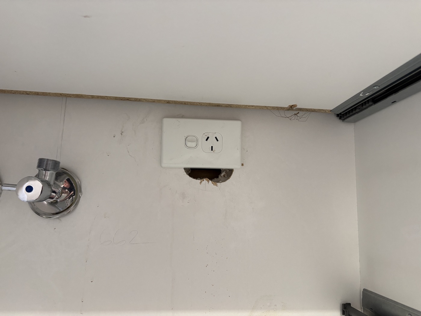 GPO outlet with large hole in wall below — a common defect found during residential electrical inspections