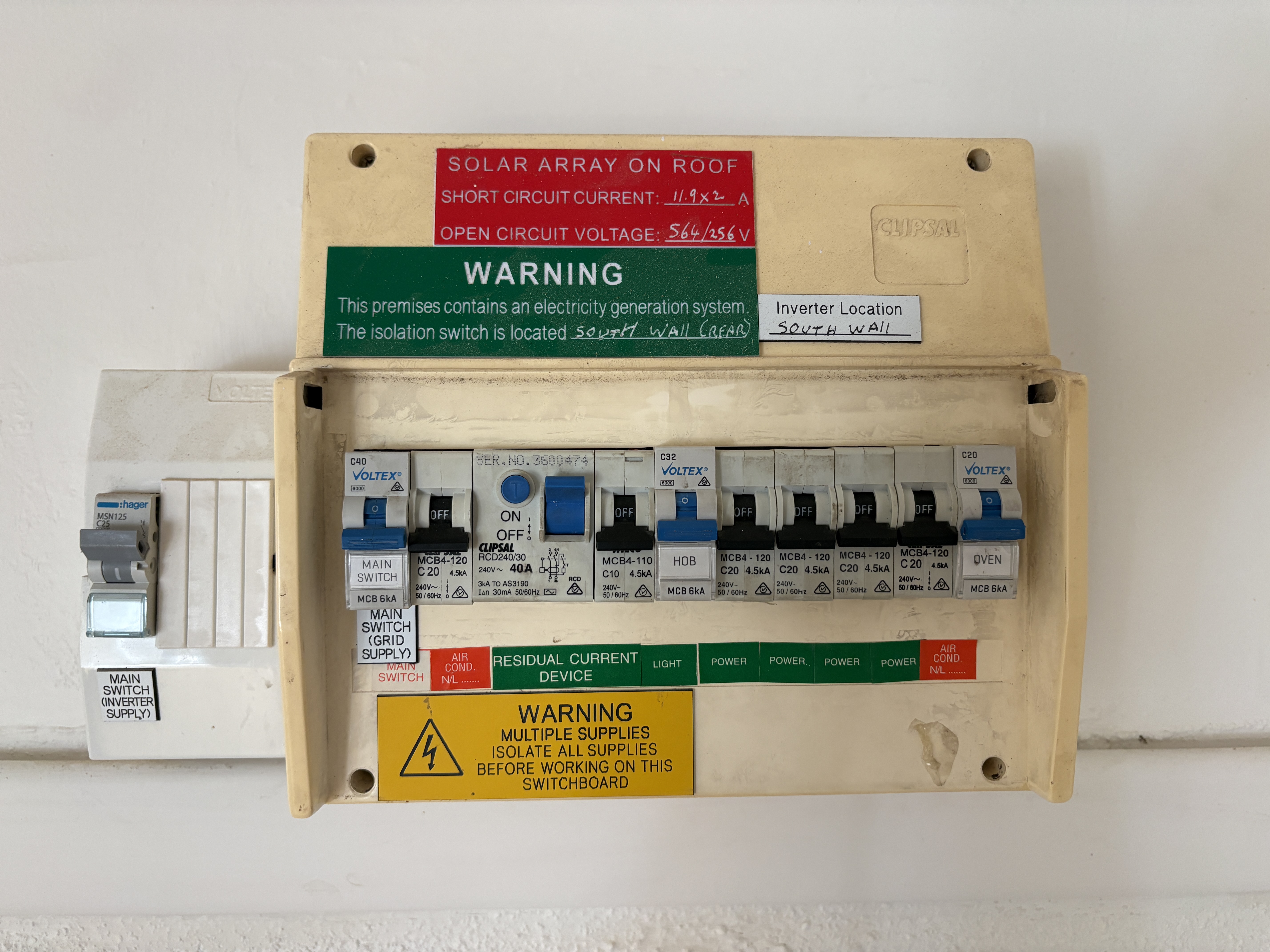 Older residential switchboard with solar warning labels